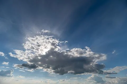Sunlit cumulus cloud with sun rays over blue sky Stock Photos
