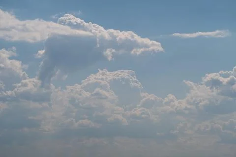 Sunlit cumulus clouds drifting across a pale blue sky Foto stock
