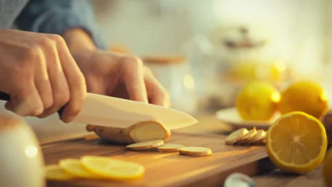 On sunlit day mans hands carefully slice fresh ginger rhizome kitchen cuttin Stock Footage 331366010