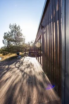 Sunlit deck and dark clad cabin with grill in northern woodland Stock Photos