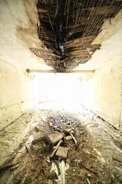 Sunlit derelict room with collapsed ceiling and debris illuminated in brigh.. Stock Photos