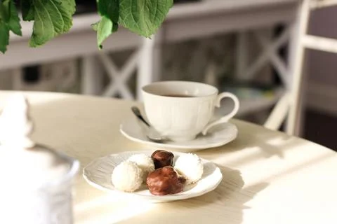 Sunlit dining table with flowers, tea and sweets Stock Photos