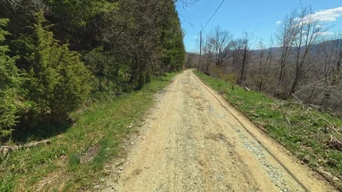 Sunlit dirt path winds through green hills. Balkan, Eastern Europe, POV Vídeo Stock 333443379