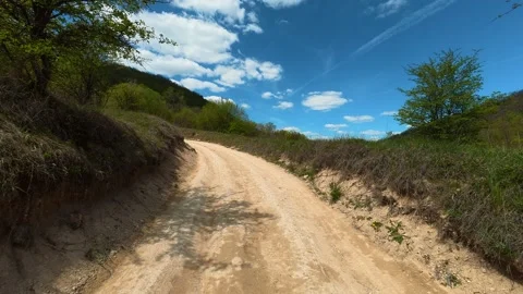 Sunlit dirt path winds through green hills. Balkan, Eastern Europe, POV Video stock 333588556