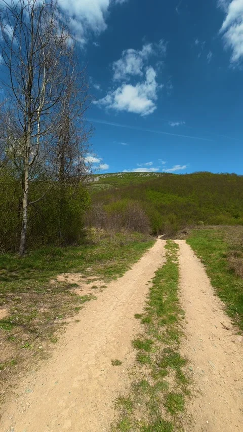 Sunlit dirt path winds through green hills. Temska River, Serbia. Vertical Видео 333700835