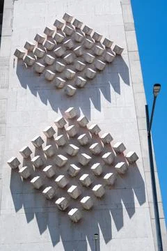 Sunlit geometric cube patterns create striking shadows on a building facade 写真素材