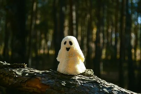 Sunlit ghost toy stands on a broken tree trunk in the forest Stock-Fotos