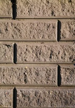 Sunlit gray brick wall with visible texture Stock Photos