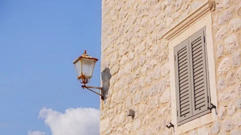Sunlit honey colored stone facade in Montenegro as camera pans right from Stock Footage 329411919