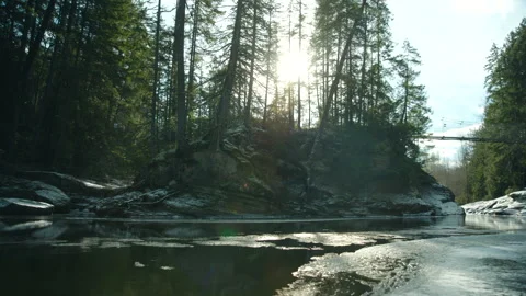 Sunlit Ice Flow: Panning Over Thawing River with Metal Bridge Stockbeeldmateriaal 262500366