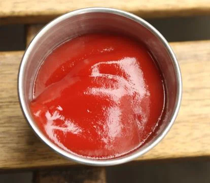 Sunlit ketchup in silver container Stock Photos