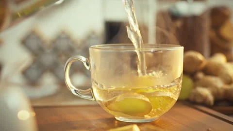 In a sunlit kitchen chopped ginger rhizome infuses steaming hot water releas Stock Footage 331353169