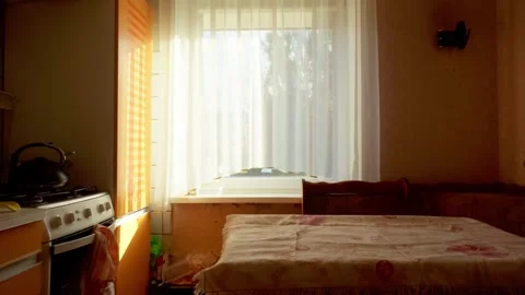 Sunlit kitchen interior with window curtain and covered table in Daugavpils home Stock Footage 343722448