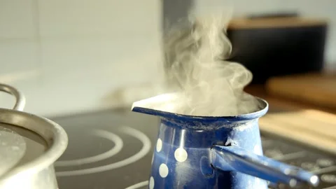 Sunlit kitchen scene shows a small blue enamel coffee pot with white polka dots Vídeos de archivo 330371365