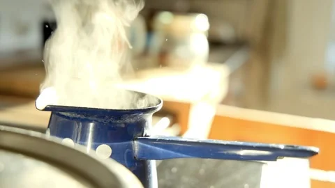 Sunlit kitchen scene shows a small blue enamel coffee pot with white polka dots Vídeos de archivo 330371432