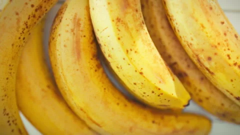 Sunlit on a kitchen table a cluster of ripe bananas with golden speckles res Stock Footage 346393152