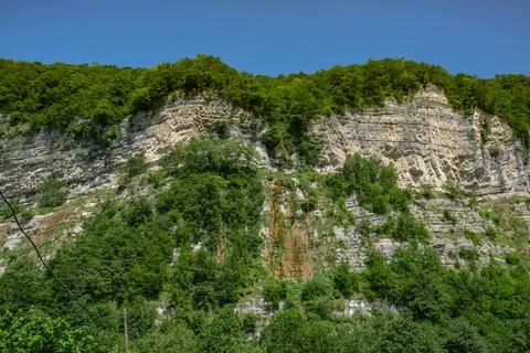 Sunlit limestone cliff with forested ridge in Adjara near Batumi, Georgia Stock Photos