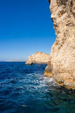 Sunlit limestone cliffs and blue waters on the coast of Comino, Malta Stock Photos