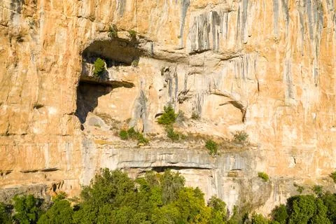 Sunlit limestone wall with dramatic rock alcoves Stock Photos