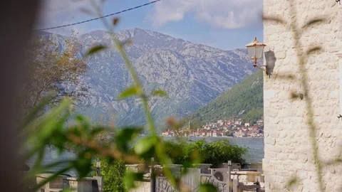 Sunlit limestone wall with shutter and rusted lantern frames a coastal town and Stock Footage 329411922
