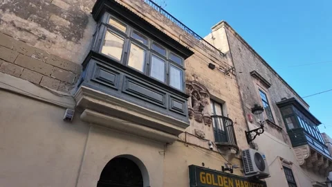 Sunlit Maltese facade with green shutters and a traditional balcony Stock Footage 317118643