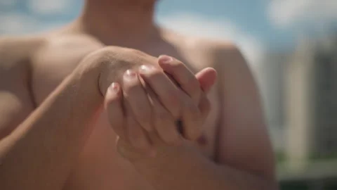Sunlit man with interlocked fingers preparing mentally, sunkissed urban rooftop Stock Footage 326490830
