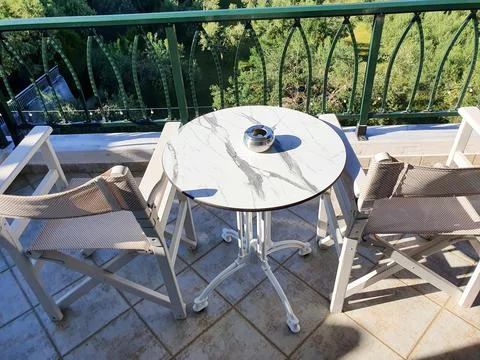 Sunlit marble-top table on a balcony with a silver ashtray and two white chai 写真素材