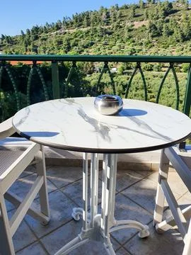 Sunlit marble-top table on a balcony with a silver ashtray Stockfoto's