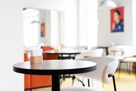 Sunlit modern cafe table chairs, empty minimalist interior with round black t Stock Photos