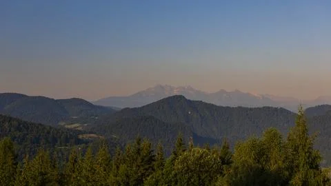 Sunlit Mountain Range Above Forested Hills in Warm Evening Light Foto stock