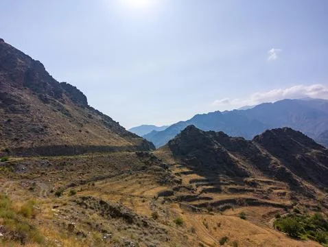 Sunlit mountain range with arid slopes and layered hills in distance Stock Photos