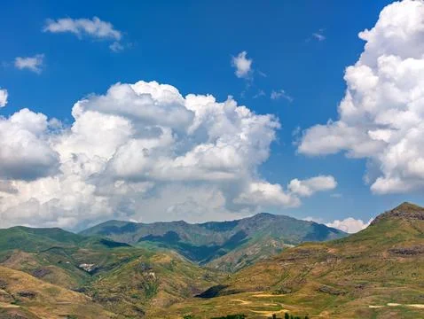 Sunlit mountain range with scattered clouds above Stock Photos