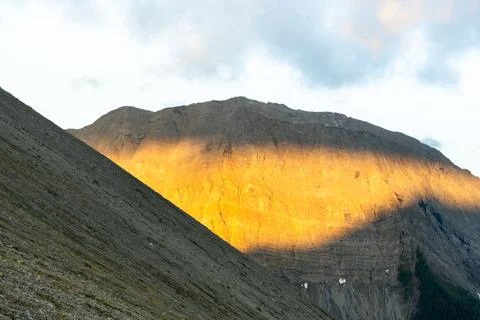 Sunlit mountain with rugged texture and dynamic light and shadow interplay. Stock Photos