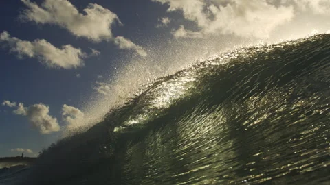 Sunlit Ocean Wave Curling Beneath Scattered Clouds and Blue Sky Stock Footage 344383879