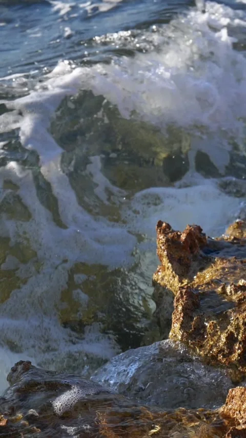 Sunlit Ocean Waves Crashing Against Dark Wet Coastal Rock Shore Stock Footage 337415444