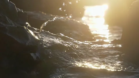Sunlit Ocean Waves Crashing Over Rocky Shoreline at Golden Hour Stock Footage 337306706