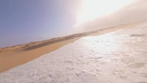 Sunlit ocean waves meet sandy beach with gentle foam. After the storm Stock Footage 345058457