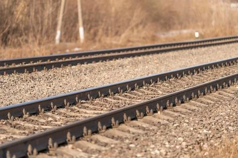 Sunlit parallel railway tracks stretching forward through ballast, dry grass, Foto stock