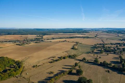 Sunlit patchwork fields and distant woodland view 스톡 사진