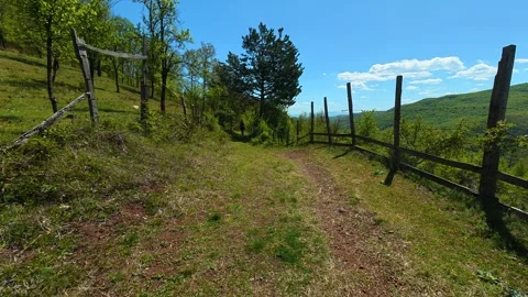 Sunlit path winds through grassy hillside. Balkan, Eastern Europe, POV 库存影片 333843454