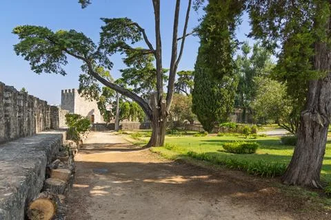 A sunlit path winds through a peaceful garden inside the thick, historic ston Fotos Stock