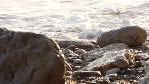 Sunlit Pebbles on Shore with Foaming Waves. Stock Footage 257207257