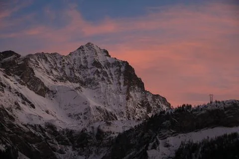 Sunlit pink clouds over Mount Arpelistock in winter. Stock Photos