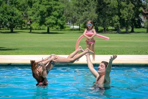 Sunlit pool, kids splash joyfully Stock Photos