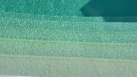 Sunlit pool steps leading into crystal clear turquoise water with sparkling Stock Footage 345036073