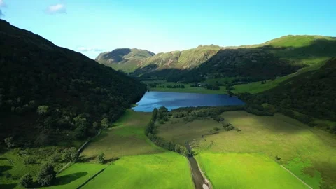 Sunlit pools moving across lush green patchwork fields on valley floor Stock-Footage 249131593