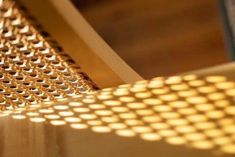 Sunlit rattan cane webbing casting geometric mesh shadow pattern on wood Stock Photos