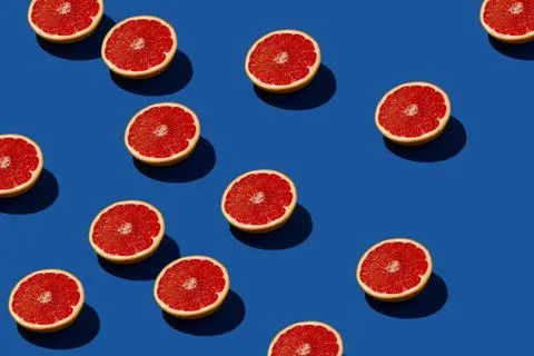Sunlit red grapefruit pattern on a blue background. Stockfoto's