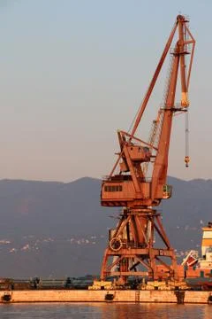 Sunlit red port crane in empty morning harbor of Rijeka Croatia Stock Photos