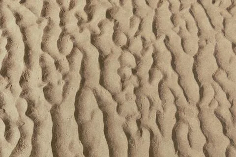 Sunlit rippled sand texture background with natural dune patterns and shadows Stock Photos